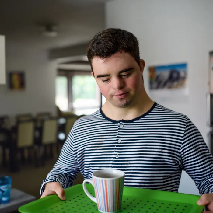 Disabled man at home with down syndrome making himself a cup of tea