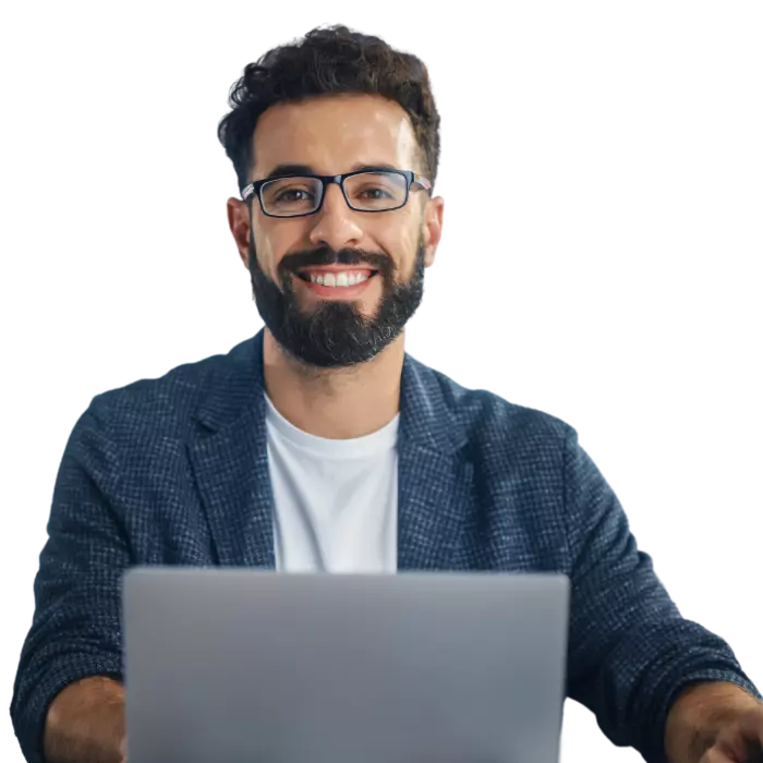 Man sitting at desk with laptop making a NDIS referral and smiling at camera